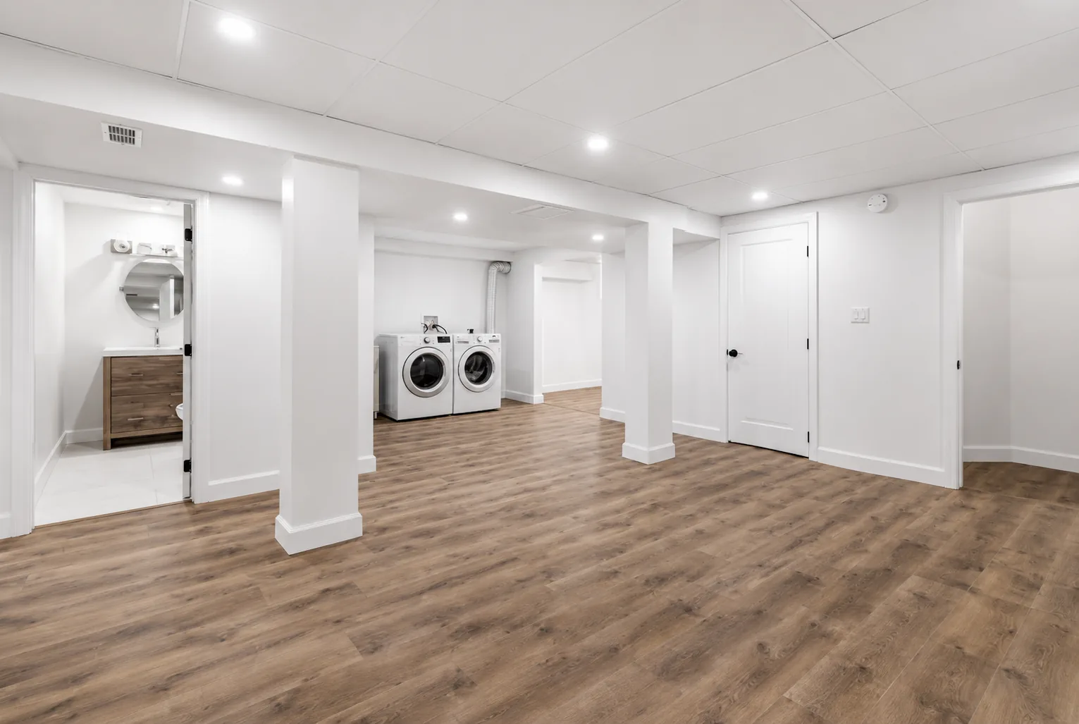 Finished basement with wood plank flooring, recessed lighting, and laundry area by DMV Home Improvement LLC in Washington, D.C.