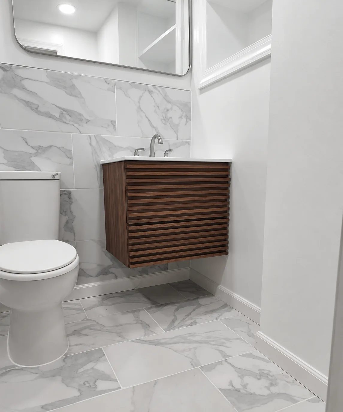 Compact full bathroom finished in marble tile with a wall-mounted wood vanity