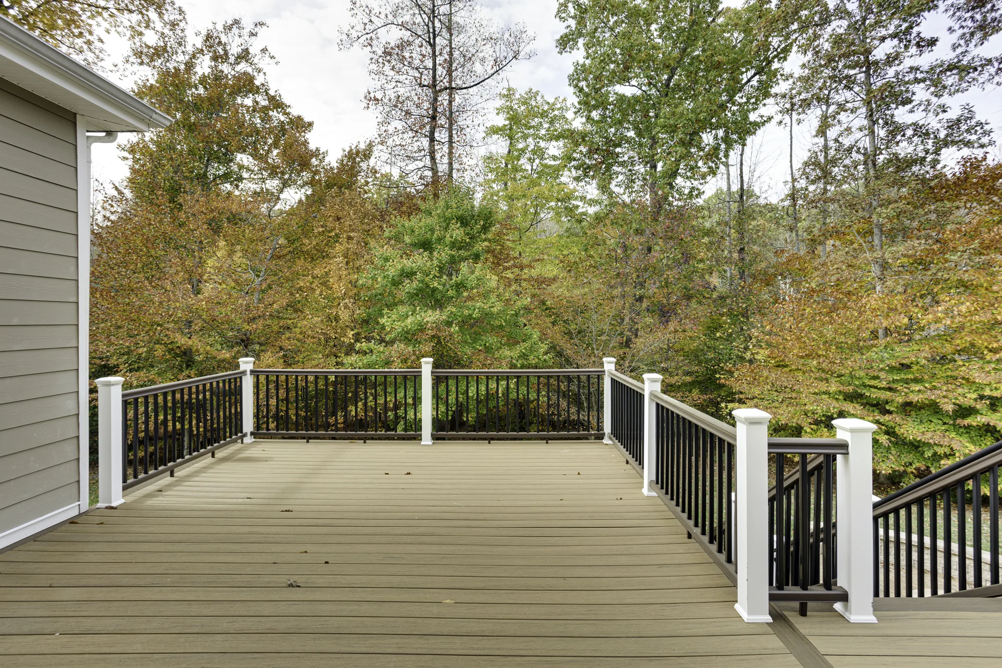 Composite deck with black and white railings and wooded backdrop