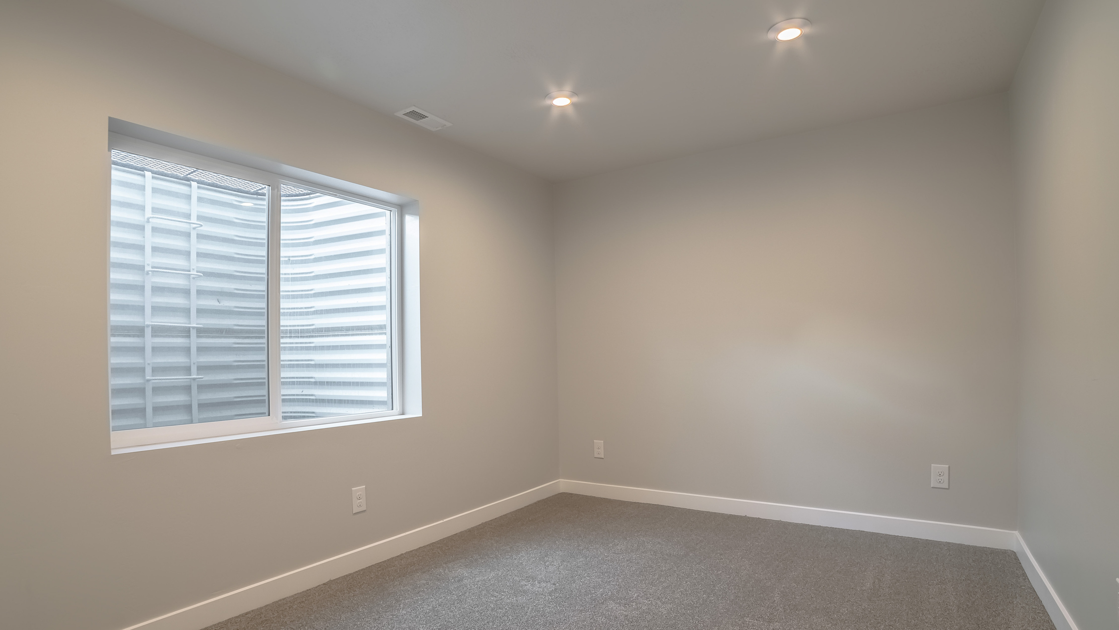 Finished basement room with egress window and recessed lighting