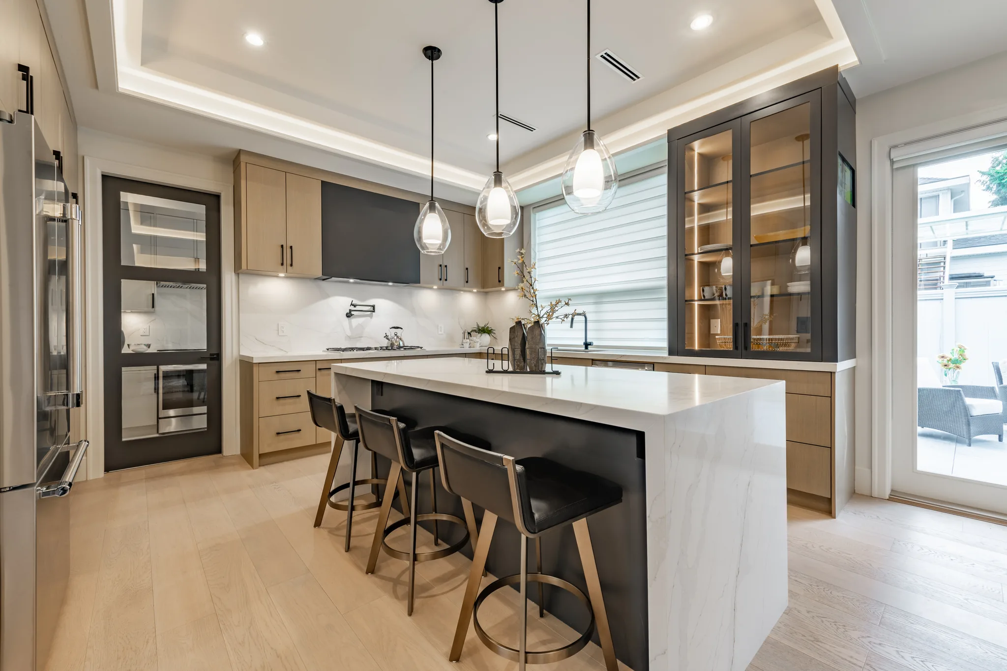 Modern dark kitchen with glass cabinet doors and waterfall island
